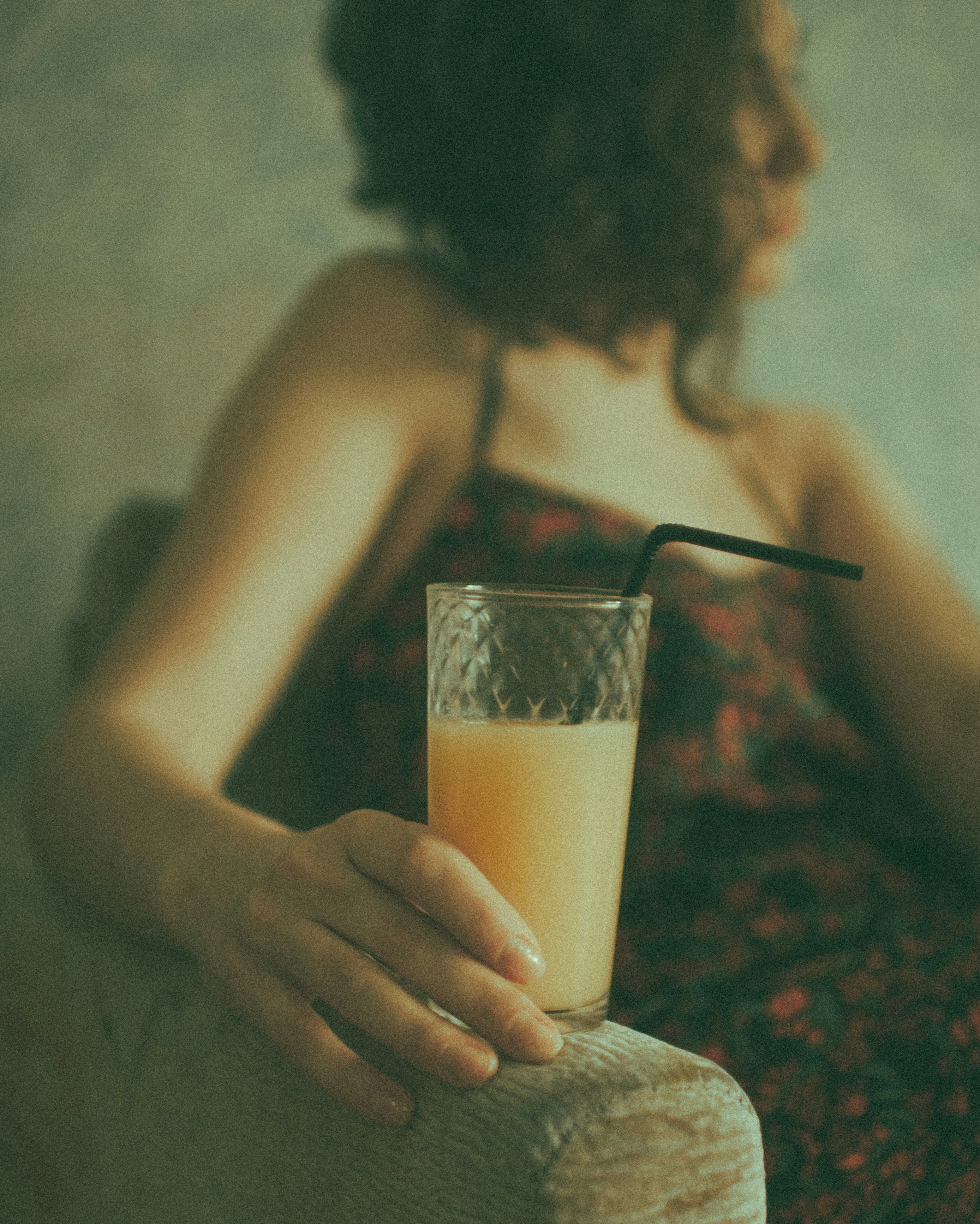 woman holding clear drinking glass with brown liquid